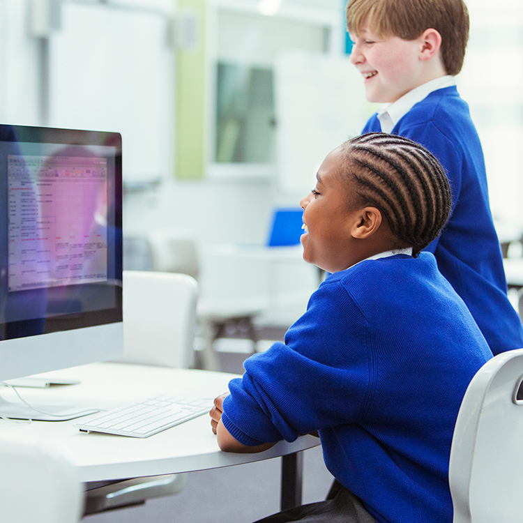 2 children smiling in a computer room